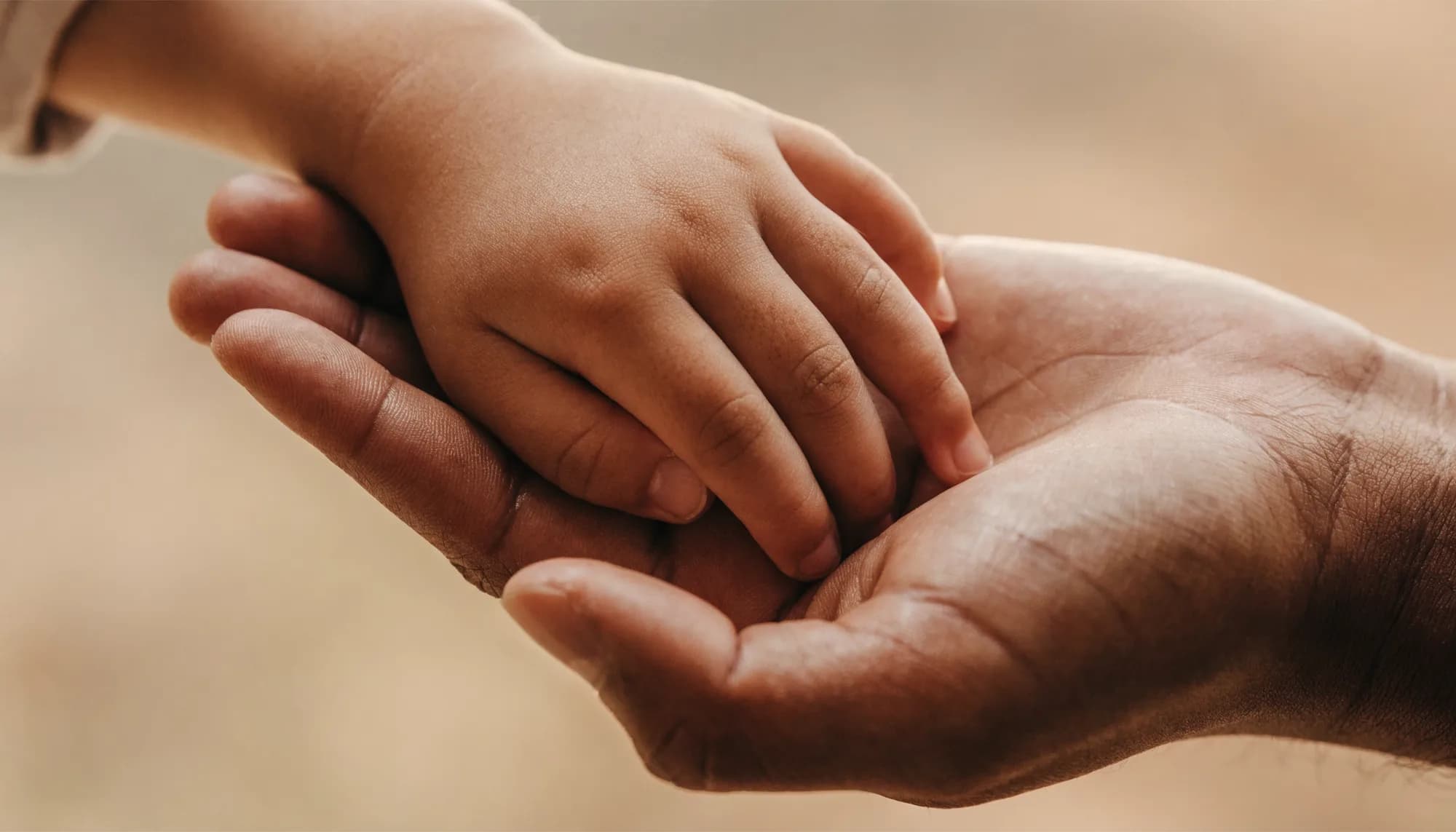 Een volwassen hand die een kinderhandje veilig vasthoudt